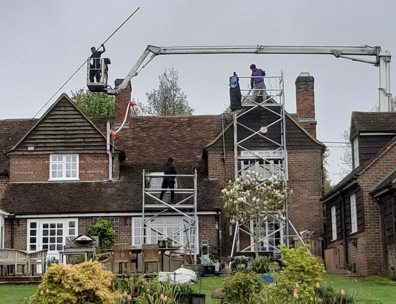 The Moss Cleaners using cherry picker and scaffolding to clean roof safely and professionally in Byfleet, {{COUNTY}}